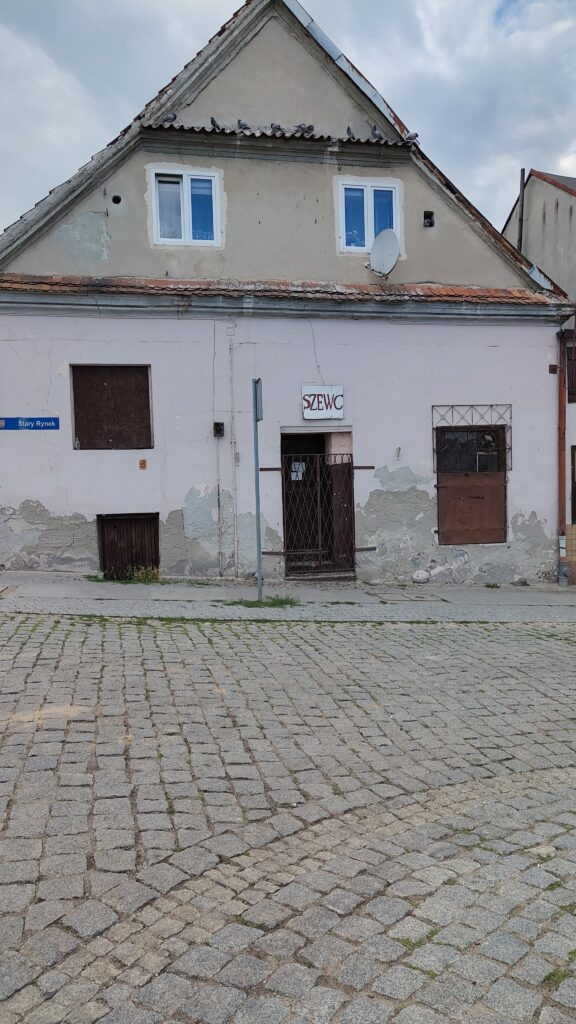 Stary szyld z napisem "Szewc" nad drzwiami kamienicy na rogu ulic Tumska oraz Stary Rynek