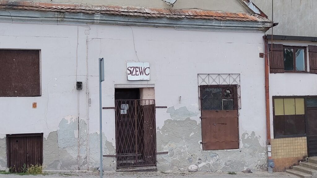 Stary szyld z napisem "Szewc" nad drzwiami kamienicy na rogu ulic Tumska oraz Stary Rynek